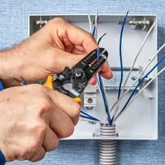 Elektryk zdejmuje izolację z przewodów. Zastanawiasz się, ile zarabia elektryk? To zależy od doświadczenia i regionu.