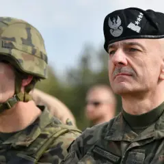 Generał Andrzejczak w czapce z orłem i gwiazdkami, obok żołnierz w hełmie.