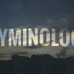 Napis KRYMINOLOGIA na tle zachodzącego słońca nad miastem.