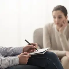 Psycholog notuje podczas sesji. Zastanawiasz się, ile zarabia psycholog? To zależy od doświadczenia i specjalizacji.