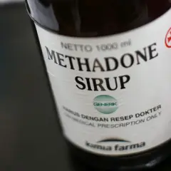 Butelka syropu metadonowego. Metadon co to? Lek wydawany na receptę, stosowany w leczeniu bólu i uzależnień.