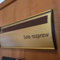 Tabliczka "Sala rozpraw" na drewnianych drzwiach. Może tu pracować referendarz sądowy.