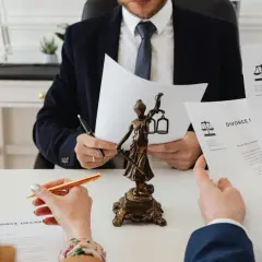 Prawnik analizuje dokumenty rozwodowe, obok figurki Temidy. Zapewnienie sprawiedliwego podziału majątku.