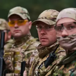 Kapral i jego drużyna w kamuflażu, gotowi do akcji. Wszyscy mają na sobie gogle ochronne i czapki.