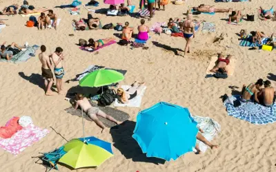 Wakacje pod gruszą na plaży. Ludzie opalają się, odpoczywają pod parasolami, ciesząc się słońcem i piaskiem.