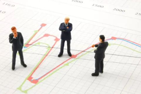 Trzej biznesmeni analizują wykresy, szukając dywersyfikacji strategii.