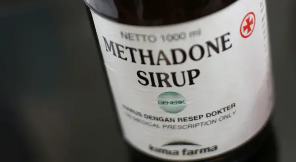 Butelka syropu metadonowego. Metadon co to? Lek wydawany na receptę, stosowany w leczeniu bólu i uzależnień.