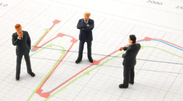 Trzej biznesmeni analizują wykresy, szukając dywersyfikacji strategii.