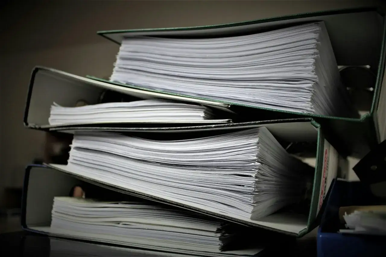 Stosy dokumentów w segregatorach, gotowe do pracy dla referendarza sądowego.