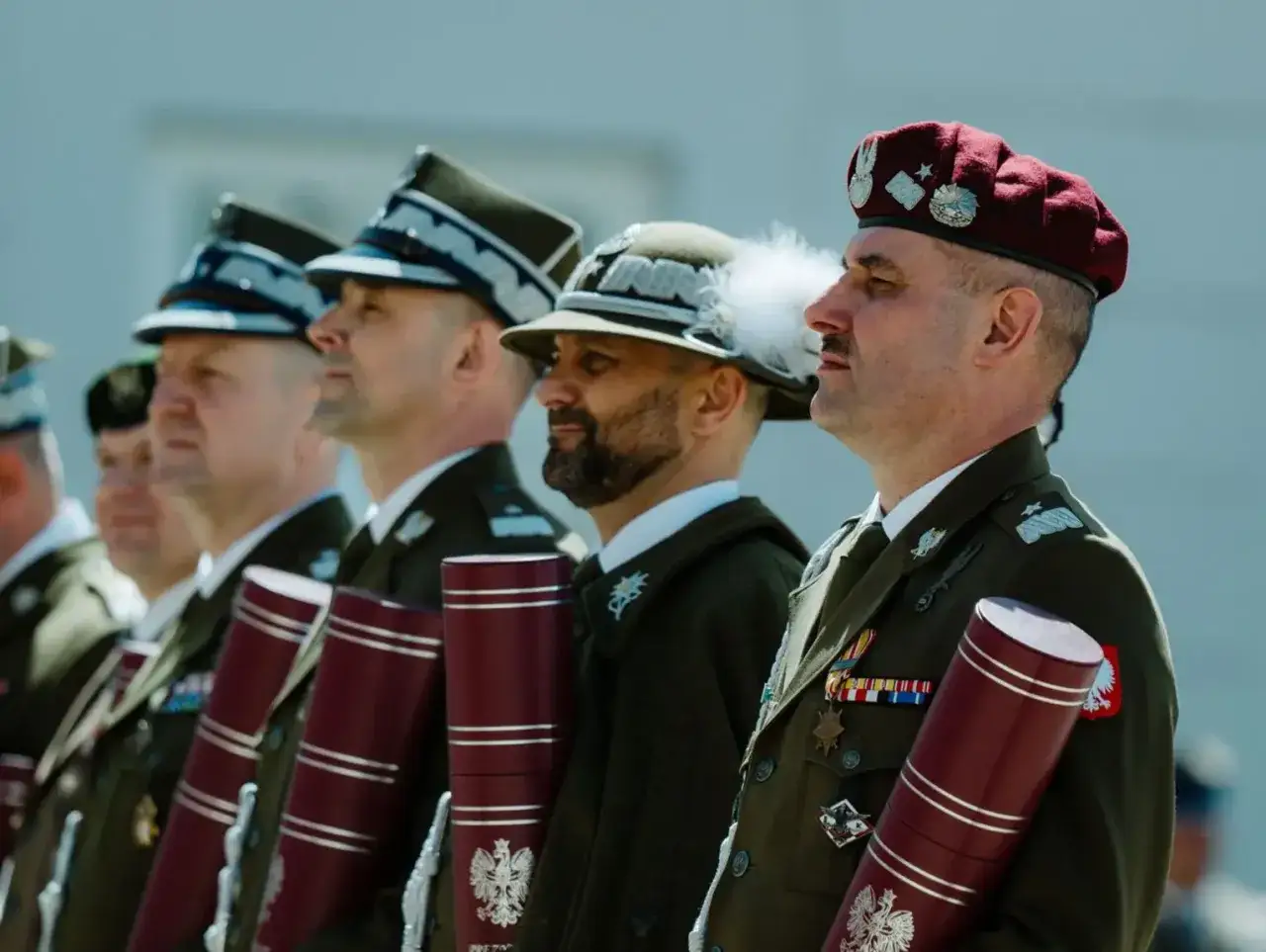 Uroczystość wręczenia nominacji generalskich. Kilku oficerów w galowych mundurach, każdy z tubą z godłem Polski.
