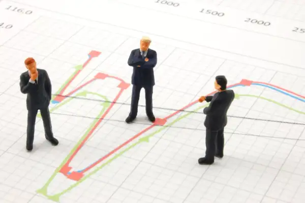 Trzej biznesmeni analizują wykresy, szukając dywersyfikacji strategii.